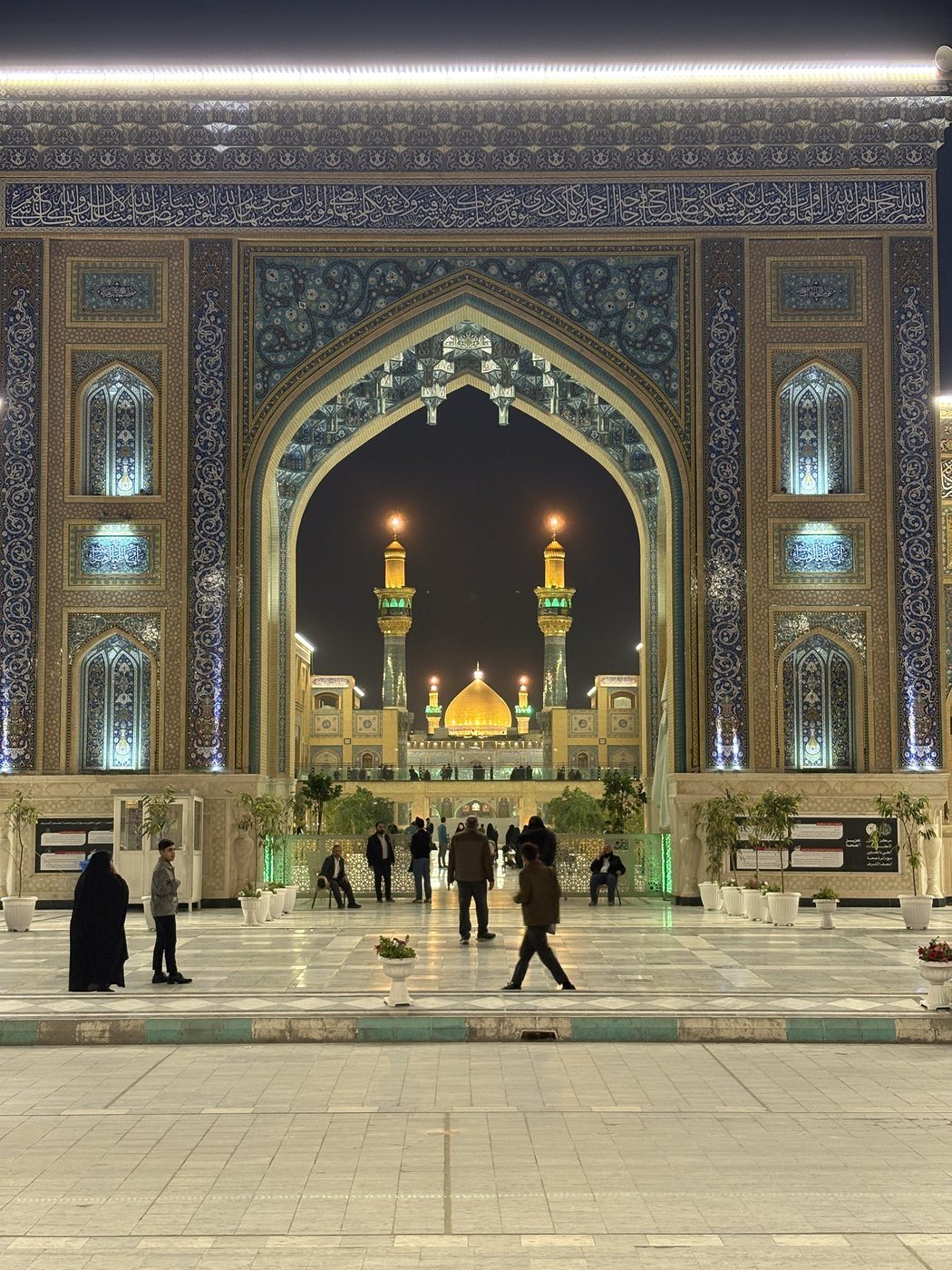 A tiled gateway frames an illuminated shrine dome at night.